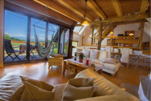 Wohnzimmer mit großem Fenster, Kamin und Blick ins Grüne